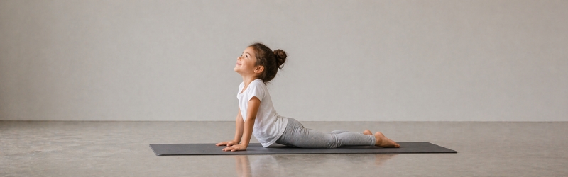 Persona joven practicando postura de cobra sobre una esterilla de yoga