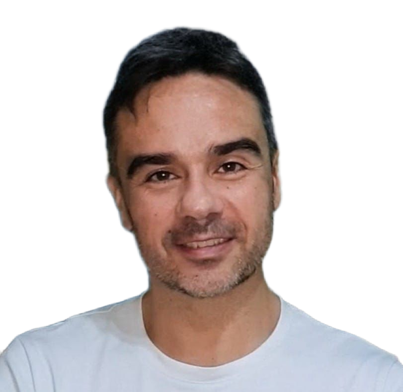 Un hombre de pelo corto y oscuro y barba incipiente sonríe. Lleva una camiseta blanca lisa y posa sobre un fondo blanco liso.