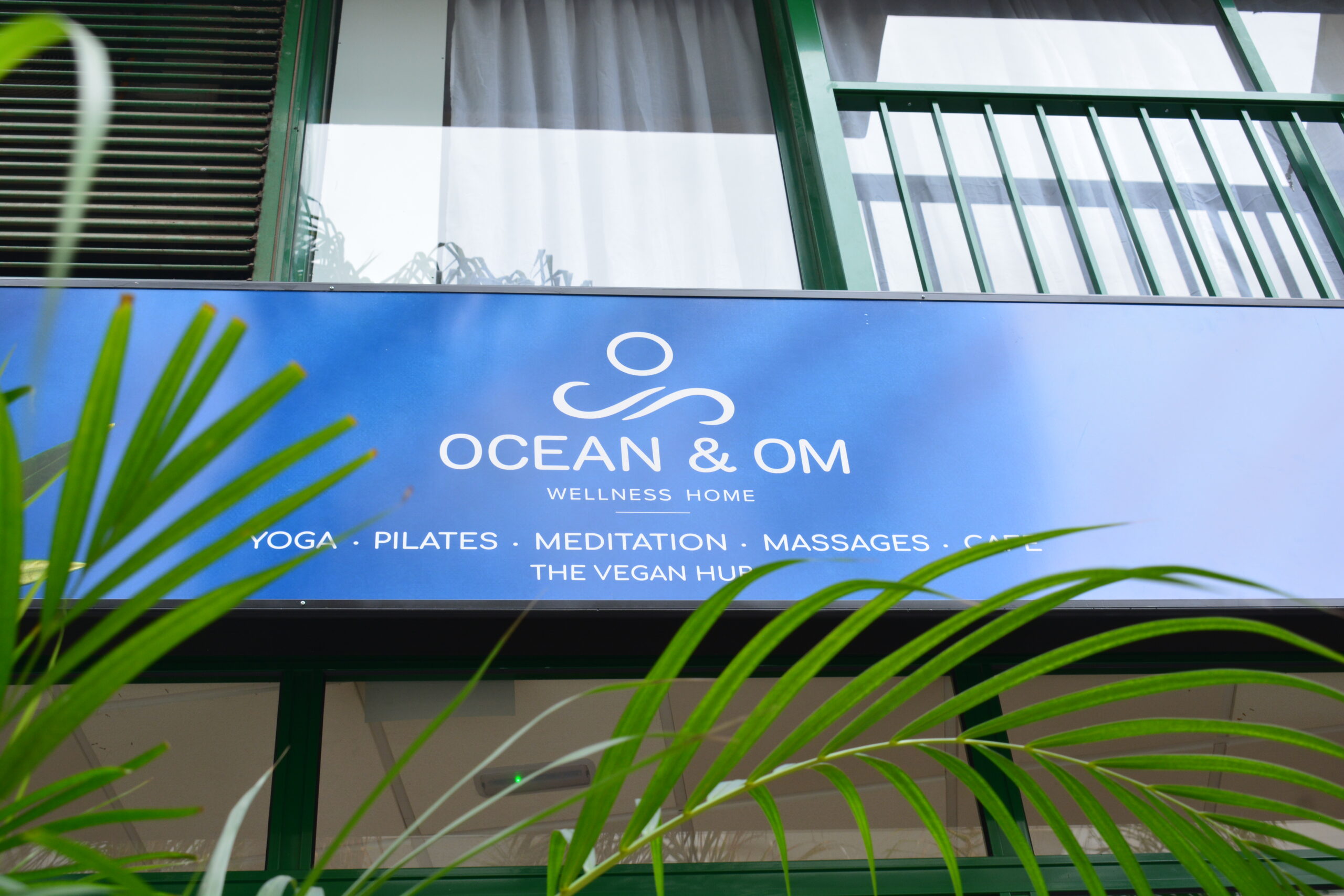 Cartel de Ocean and Om Wellness Home rodeado de vegetación