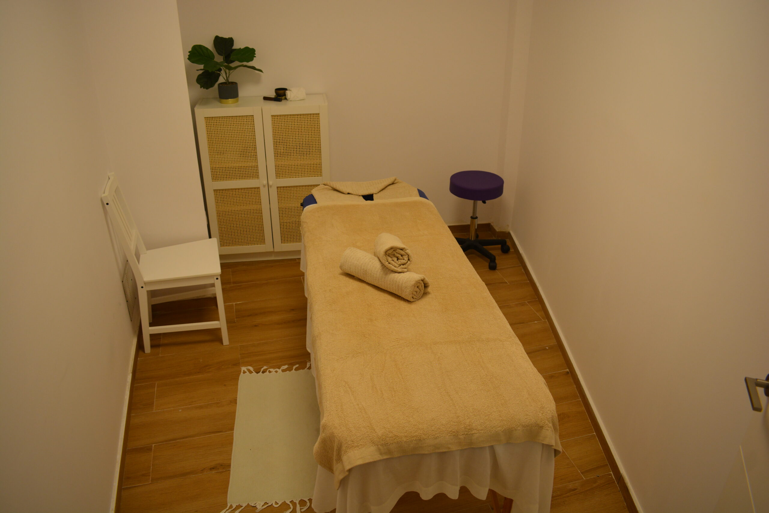 Tidy massage room at Ocean and Om with a treatment table, towels and plants
