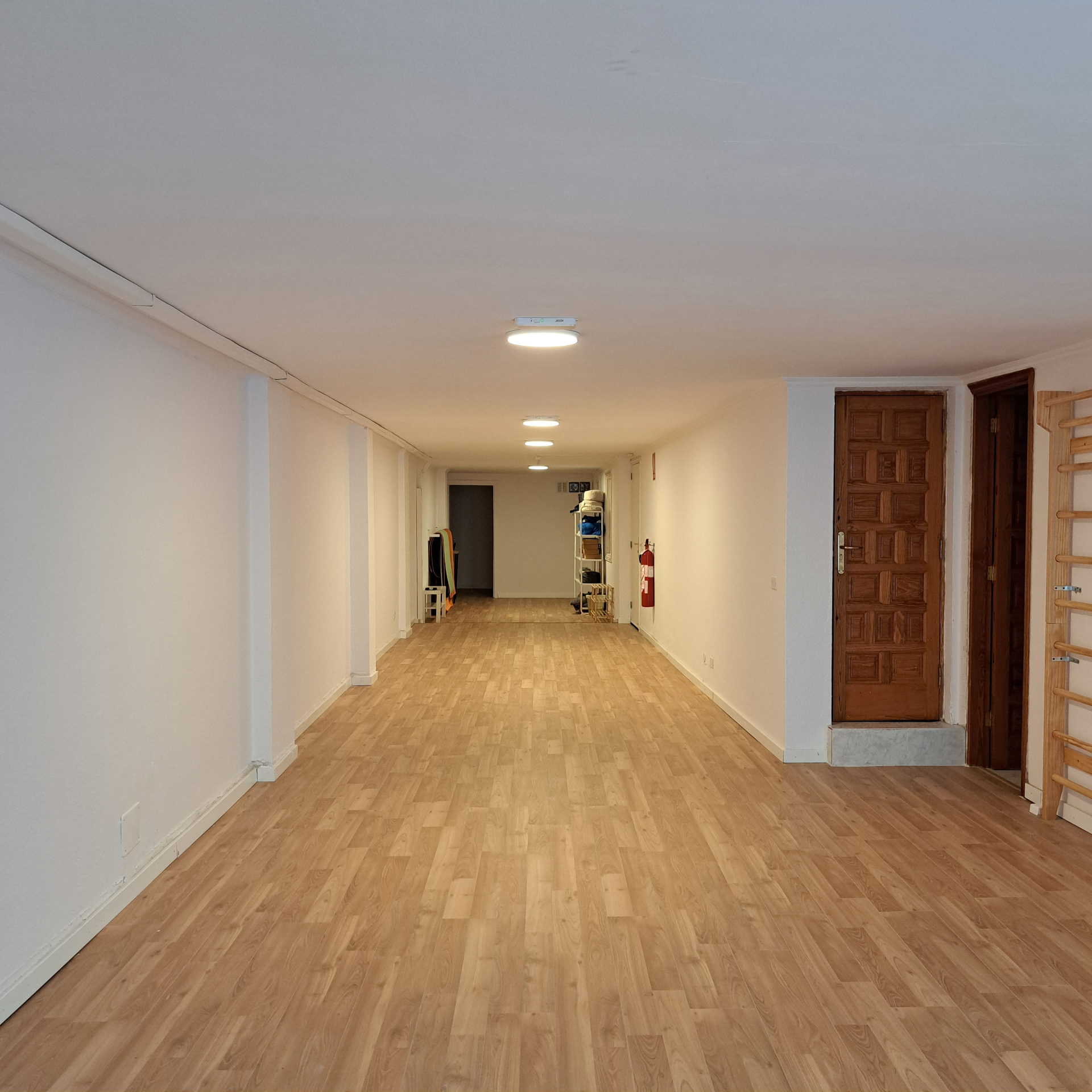 Sala despejada con suelo de madera, paredes claras y luces de techo.