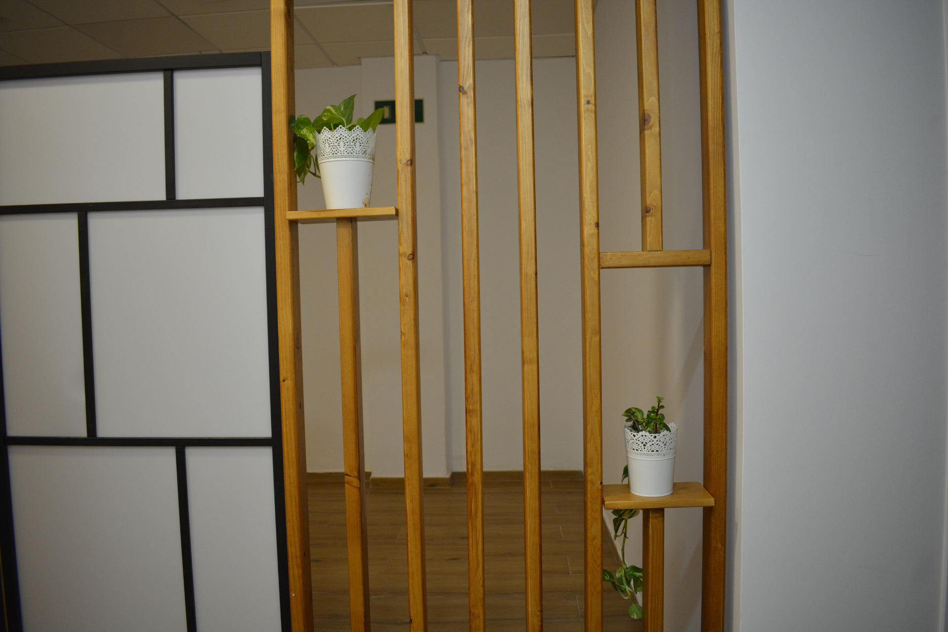 Divisor interior de madera con listones verticales y pequenas plantas.