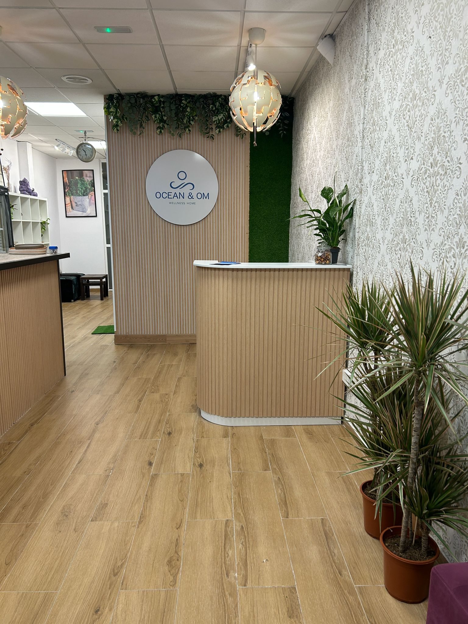 Recepción amplia de Ocean and Om con mostrador claro, plantas y suelo de madera